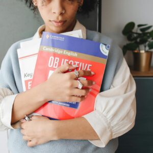 Young woman holding language study books indoors, symbolizing education and learning.
